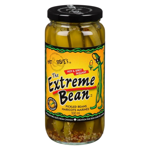 The Extreme Bean Haricots Marinés Épicés et Piquants Pot de 500 ml Montrant des Haricots Verts Entiers en Saumure avec des Épices, avec une Étiquette Jaune avec Texte Noir et Rouge Audacieux et un Personnage de Haricot de Dessin Animé, Convient pour Ajouter une Saveur Croquante et Audacieuse aux Recettes Ou aux cocktails.