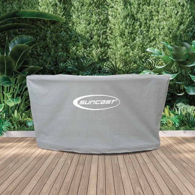 Suncast - Bar Cover - Cool Gray made of 600-denier polyester with waterproof lining and anti-UV coating, covering a backyard entertaining bar on a wooden deck with green plants behind, featuring two adjustable drawstring cords for a secure, weather-resistant fit.