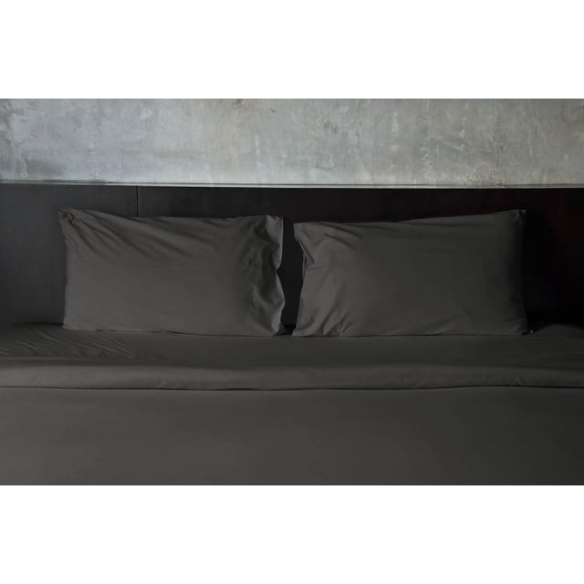 Cotton Bed Sheet Sets, 300 Thread Count, Johnson Home Fashions in dark grey with a fitted sheet and two pillowcases on a bed framed by a dark wood headboard and a textured grey wall, made from breathable, lightweight cotton with a smooth sateen weave for all-season comfort, also suitable for creating a minimalist bedroom aesthetic.