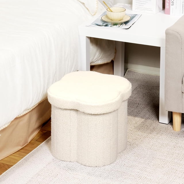 PINPLUS 12.6" white ottoman storage box with a flower-shaped design, featuring a soft cream teddy velvet finish. This foldable storage seat box doubles as a small footstool and toy chest, ideal for living rooms, bedrooms, or children's spaces. The ottoman includes a hidden storage compartment for organizing items like toys, blankets, or magazines. Positioned next to a white side table in a cozy room setting.