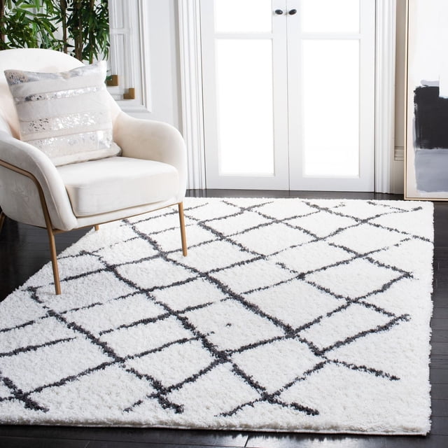 SAFAVIEH Berber Santana Tapis Shag Géométrique pour Aire avec un Poil Shag Bas Blanc et des Motifs Géométriques en Losanges Noirs, Posé sur des Planchers de Bois Franc Sombres dans une Pièce Lumineuse avec des Portes Françaises Blanches, Complété par un Fauteuil Rembourré Crème avec des Pattes Dorées et un Coussin Décoratif, Idéal pour Ajouter Chaleur et style à la Déco de la Maison.
