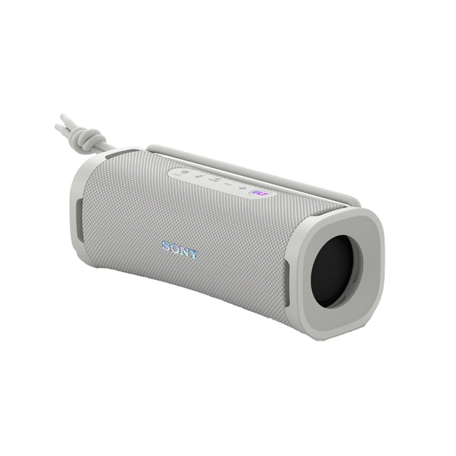 Sony ULT FIELD 1 Wireless Portable Speaker in off white with a compact cylindrical design, textured fabric grille, top control panel including a purple ULT bass boost button, and a detachable multi-way strap. It features IP67 waterproof, dustproof, rustproof, and shockproof ratings, offering up to 12 hours of battery life, suitable for outdoor use and stereo pairing.