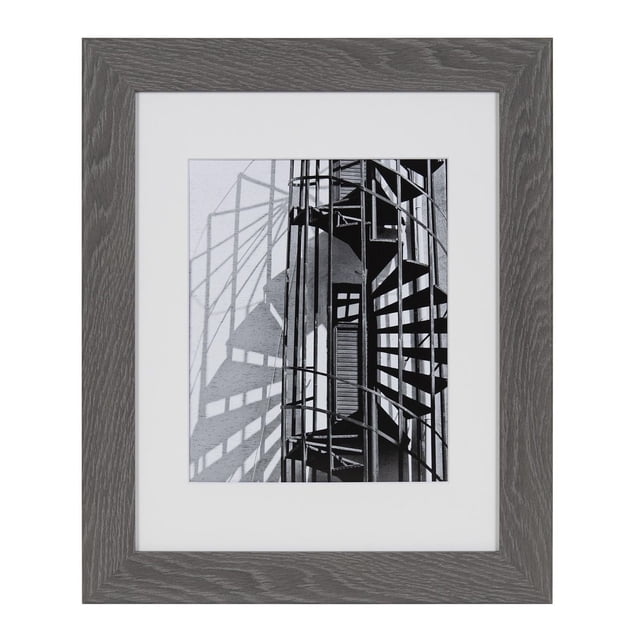 hometrends Museum Grey Picture Frame with a wide grey wood grain profile and a crisp white mat holding a black and white photo of a spiral staircase casting shadows, fits 8x10 inch photos with mat or 11x14 inch photos without, suitable for gallery wall arrangements with easy horizontal or vertical hanging.