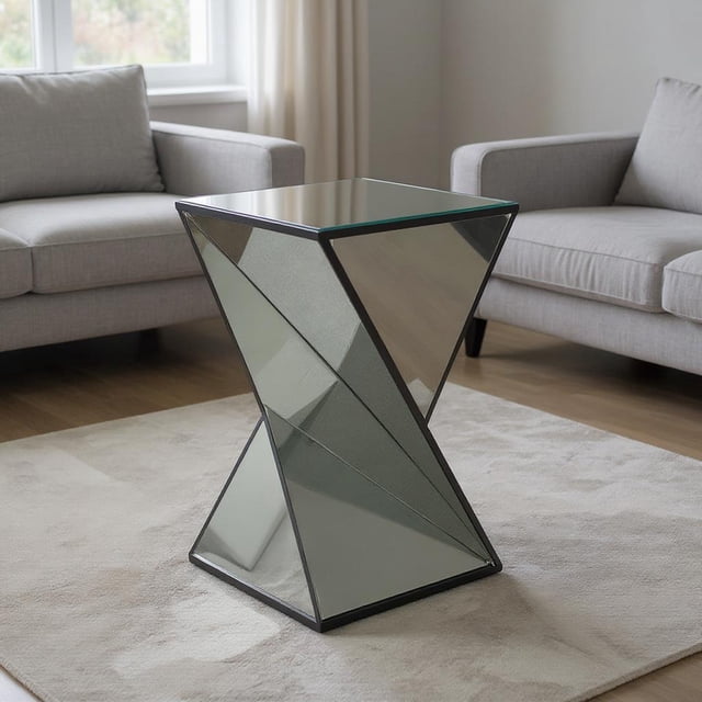 Homy Casa Decorative Mirrored Pedestal Table with sculptural geometric form and beveled mirrored surfaces, reflecting light to enhance room brightness, placed on a beige rug between two grey sofas in a modern living room, often used as a stylish accent or side table.
