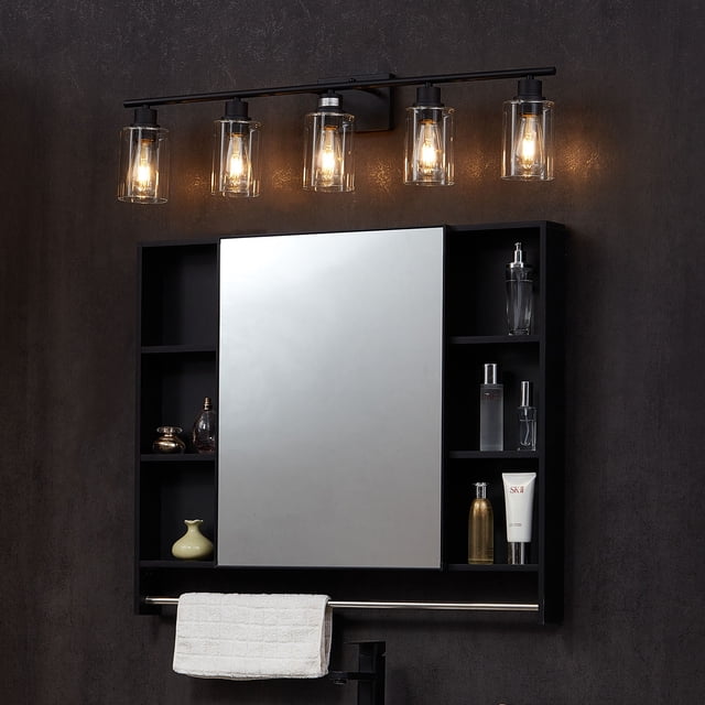 VEVOR 5-Light Modern Bathroom Vanity Light, a 37.1-inch wall light fixture, installed above a bathroom mirror. The fixture features five clear glass shades with E26 bulb bases, providing bright and shadow-free illumination. The black metal frame offers a sleek, modern design suitable for various spaces, including bathrooms and bedrooms. The light is shown in a dark bathroom setting with a mirror and shelving below.