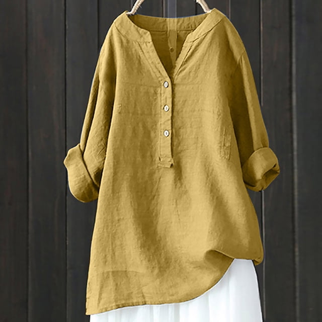 Pisexur Womens Cotton Plus Size Tops Solid Oversized Tees Loose T Shirts Half Sleeve V Neck Color Block Tunic Tops. A mustard yellow, loose-fitting tunic top made of a cotton and linen blend, featuring a V-neckline with button detailing and 3/4 roll-up sleeves. The lightweight and breathable fabric is suitable for casual, work, or vacation wear during spring, summer, and autumn. Shown hanging against a dark wooden background.