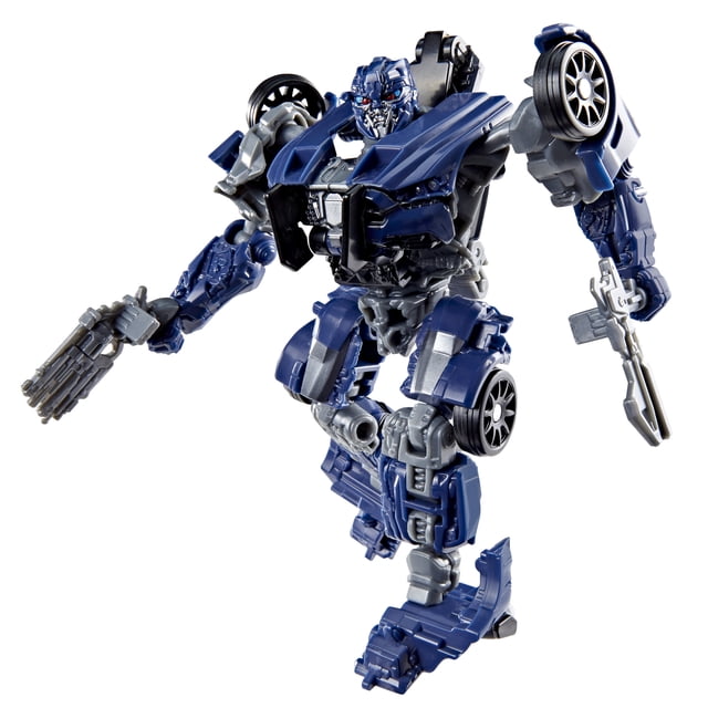 Transformers Studio Series The Last Knight Deluxe Class Barricade action figure in robot mode, 4.5 inches tall, featuring blue and gray articulated parts, detailed mechanical face, and blaster accessories attached, posed dynamically on a white background as a collectible TV and movie action figure suitable for display or play.