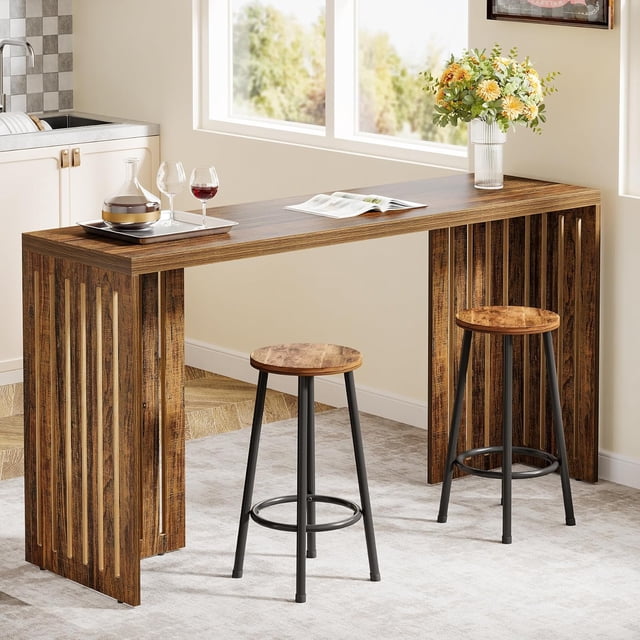 Tribesigns table de bar de 63 Pouces avec Fini Brun Rustique, Conçue comme une table de pub Style Ferme avec base à Persiennes et Lignes Épurées. la table Rectangulaire Étroite Convient aux Petits Espaces et Comprend Deux Tabourets Assortis. Fabriquée en MDF de Haute Qualité avec un Plateau Robuste de 1,57 Pouces d'Épaisseur et des Pieds en V pour la Stabilité. Convient pour Être Utilisée comme table de Comptoir, de bar à Café Ou d'Espace de Travail. Positionnée dans un Décor de Cuisine Lumineux avec des Verres à Vin, une carafe et un vase de Fleurs sur le Plateau.