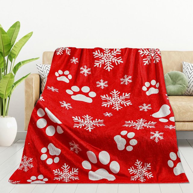 TIMIFIS Throw Blanket, a flannel blanket with a vibrant red design featuring white animal paw prints and snowflake patterns. Made of 100% polyester, this lightweight and durable blanket measures 75x100 cm, perfect for snuggling on couches, beds, or during travel. Ideal as a holiday or birthday gift for animal lovers and parents, it is shown draped over a beige sofa in a cozy living room setting.