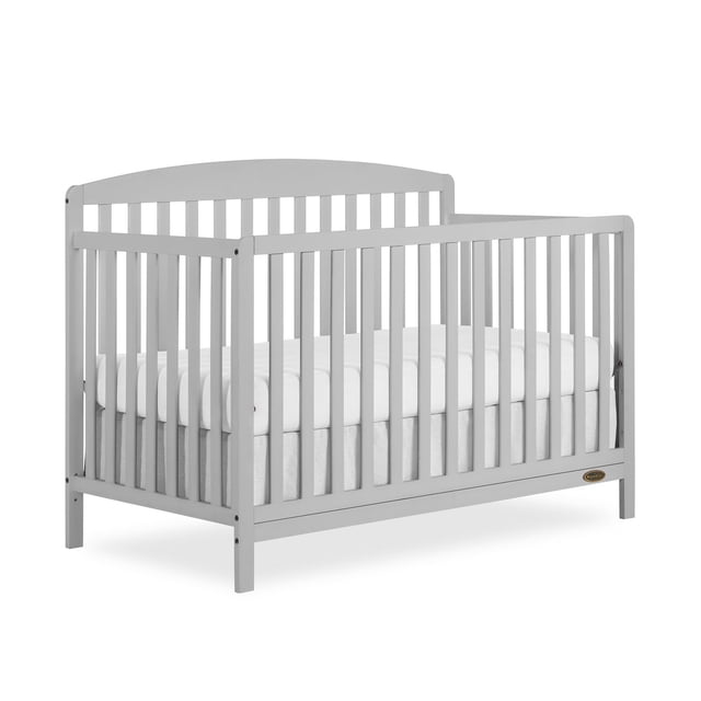 Dream On Me Odelle 5 in 1 Convertible Crib front-facing white wooden crib with vertical spindle slats, visible 3-position adjustable mattress height set to middle; converts to daybed, toddler bed or full-size bed (conversion kit sold separately). Dimensions 54.72" L x 29.33" W x 40.16" H.