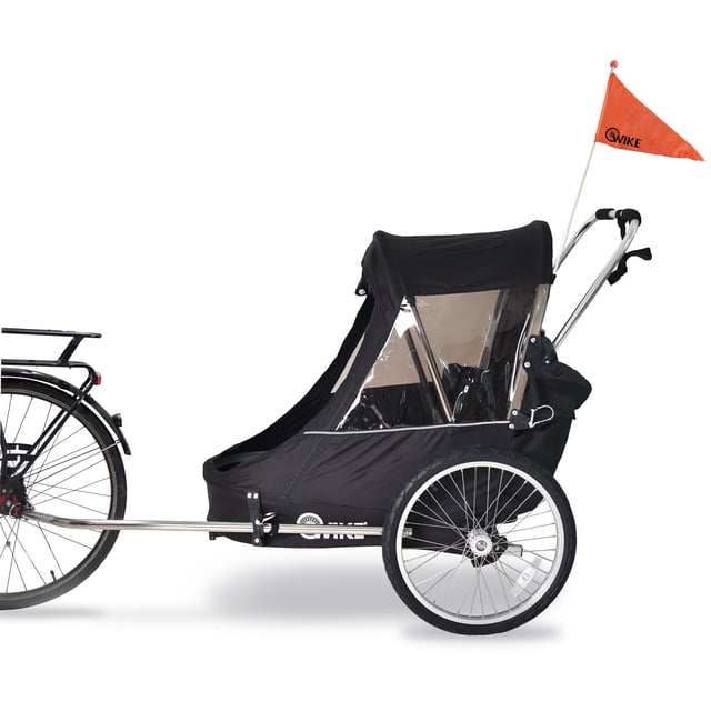 Wike Premium Double Children's Bike Trailer shown in a side view, attached to a bicycle. This versatile trailer features a lightweight, sturdy frame with a black fabric cover, large transparent windows, and an orange safety flag. It includes a stroller and jogging kit, making it suitable for biking, strolling, or jogging with two children. The trailer also has rain and bug screens for added protection.