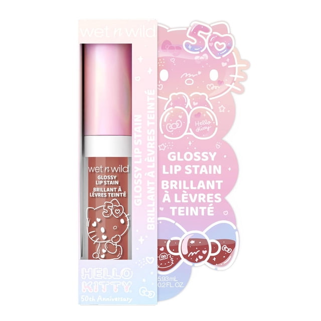 Hello Kitty Glossy Lip Stain by wet n wild in warm brown nude shade, shown in a pastel pink and purple box with white 50th anniversary text, featuring a clear tube with a pink metallic cap and Hello Kitty graphics, ideal for bold, glossy lip colour with a lightly scented formula.