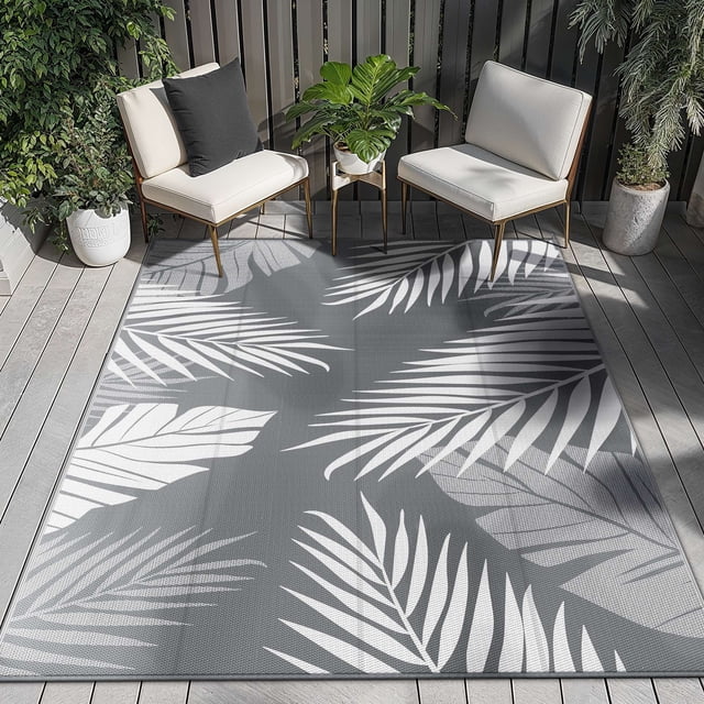 DEORAB 6'x9' Tapis d'Extérieur Imperméables pour Patio, Légers et Réversibles, en Plastique Gris et Blanc, Mettant en Valeur un Motif Feuillu. Parfaits pour les patios, le camping Ou les Sorties à la Plage, le Tapis Est Fait de Plastique Recyclé Écoresponsable, Offrant une protection UV, une Résistance aux Taches et un Nettoyage Facile. Exposé sur un Patio avec des Chaises Blanches, un Coussin Noir et des Plantes en Pot, Il Comprend des Bords Renforcés, des Anneaux d'Angle et des Piquets de Sol pour la Stabilité.