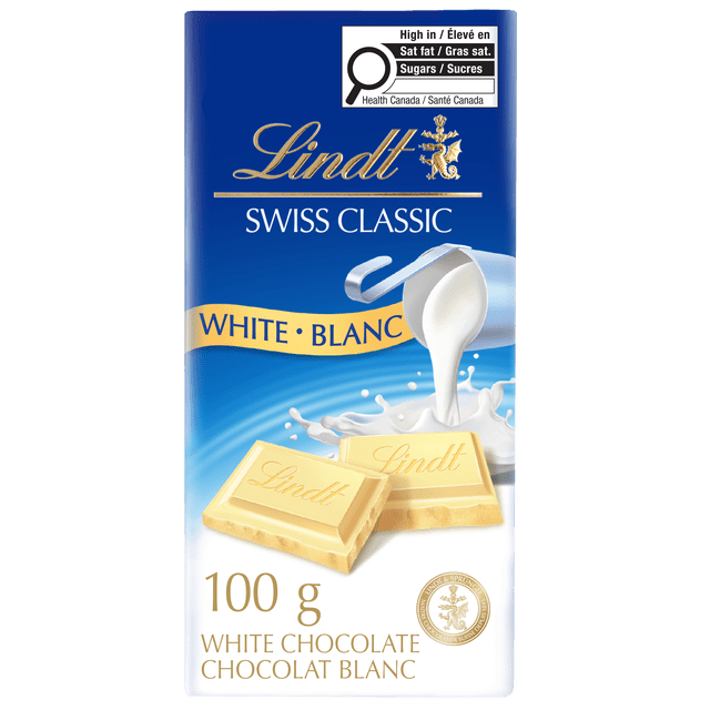 Lindt SWISS CLASSIC White Chocolate Bar, 100 g, with two white chocolate squares embossed with the Lindt logo, pouring milk splash on a blue and white background, highlighting its creamy texture and rich Swiss chocolate flavour, ideal as a gourmet treat or gift.