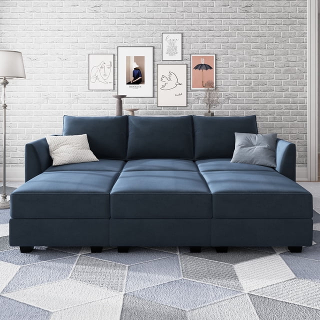 HONBAY Elegant Velvet Convertible Sleeper Sectional Sofa Bed with Storage in navy blue, displayed in a contemporary living room with a white brick wall and decorative framed artwork. The modular sofa includes hidden storage under each seat and can be rearranged into a sleeper sofa configuration. Overall dimensions are 87 W x 55.90 D x 33.86 H inches, with a bed size of 76.8 W x 51.2 D inches.