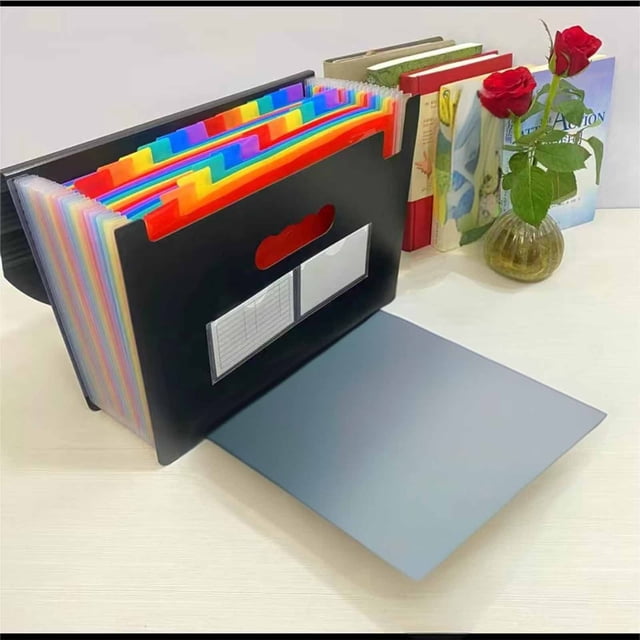 TopLLC Organisateurs et Rangement de Garde-Robe, Pochette Portable A4 pour Feuilles de Test avec un design Multicolore et 12 Compartiments pour un Rangement de Grande Capacité. Fabriquée en Plastique Écologique, Elle Présente une Fermeture à Boucle Sécurisée et une Poignée pour la Portabilité. la Pochette Est Affichée sur un Bureau avec des Livres et un vase en Arrière-Plan.