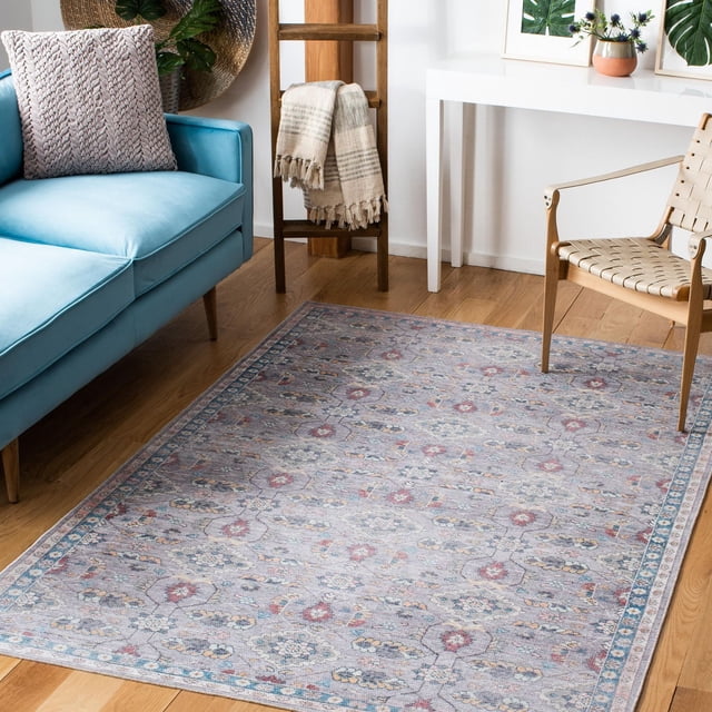 SAFAVIEH Serapi Winnie Oriental Area Rug featuring a traditional floral pattern in muted blue, red, and beige tones, power loomed with cotton, viscose, and polyester in a soft close-cut pile. It is placed on a hardwood floor between a light blue sofa and a woven strap wooden chair, with a wooden ladder holding a beige throw and a white console table with botanical artwork. Ideal for enhancing living room décor with a blend of classic and contemporary style.