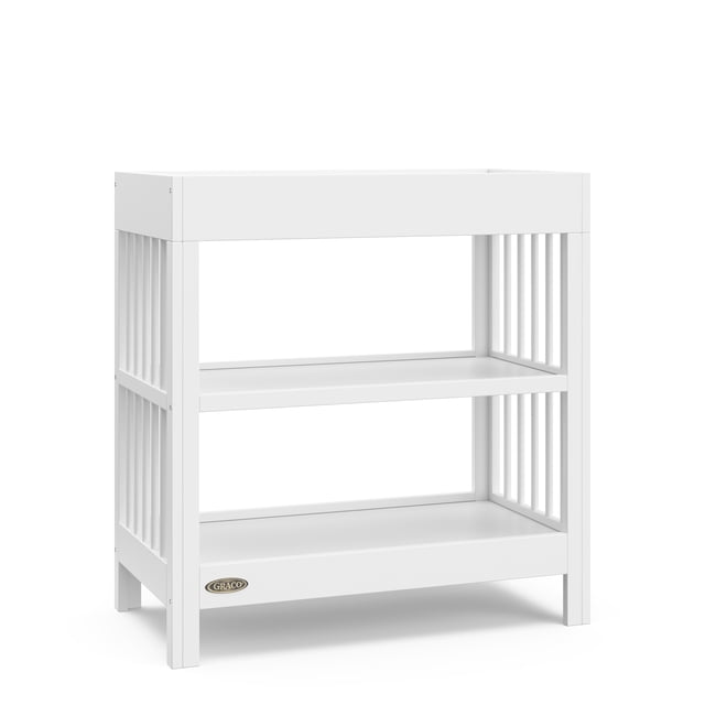 Graco Teddi Changing Table, White, front view showing a pine wood frame with white finish, two open storage shelves, and a raised changing surface with safety rails, designed for nursery organization and easy pairing with various crib styles.