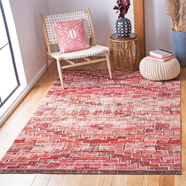 Safavieh Montage Bryon Tapis d'Extérieur Abstrait pour Aire avec Motif Géométrique Rouge et beige, Fil Synthétique Tissé Mécaniquement pour Résistance à l'Eau et au Soleil, Placé sur un Plancher de Bois Franc Clair à Côté d'Une Chaise en Bois Tressée avec un Coussin à Motif Rose, une table d'Appoint en Osier avec un vase Noir et Blanc, et un pouf beige Tricoté avec des Livres.