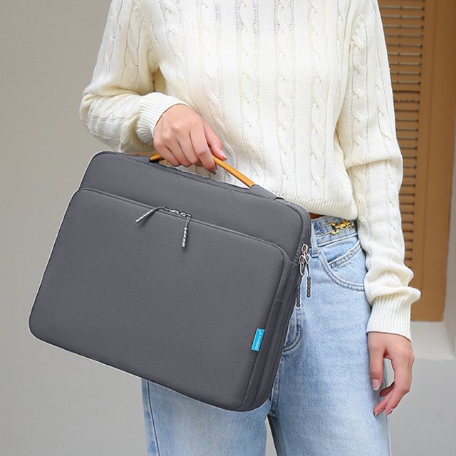 15.6-inch laptop bag in grey, designed as a portable computer case with shockproof and scratch-resistant waterproof fabric. Features 360° corner protection, multiple compartments for accessories, and a trolley fixed strap for travel convenience. Lightweight and ideal for work and leisure use.