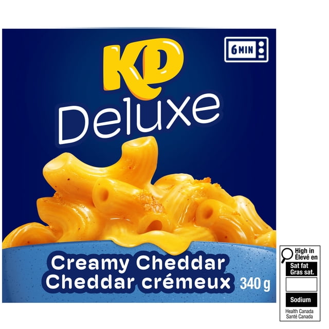 KD Deluxe Creamy Cheddar Macaroni and Cheese Frozen Dinner 340g box showing close-up of elbow macaroni coated in creamy cheddar cheese sauce on a blue background with 6-minute microwave cooking icon and Canadian nutrition labels.