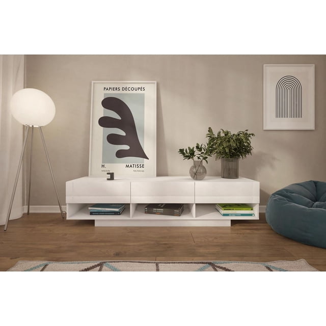 Stereo 3 Drawer 72-Inch TV Stand in white melamine finish with three metal-slide drawers and three open cubbies for electronic components and books, positioned against a beige wall with modern framed art, next to a tripod floor lamp and a blue bean bag on wood flooring, ideal for media organization in living rooms.