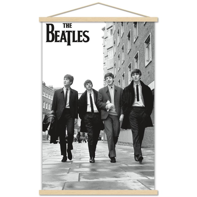 The Beatles - In London Wall Poster, 22.375" x 34" featuring a black and white photo of four men walking on a paved city street between brick buildings, dressed in suits and coats, with The Beatles logo in bold black letters at the top left, printed on glossy poster paper ideal for wall art and room décor.