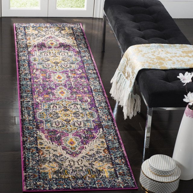 Safavieh Monaco Durward Traditional Area Rug 2'2"x8' runner featuring a Bohemian-chic Persian design in purple, blue, yellow, and cream, made of durable polypropylene with mixed loop pile, placed on dark hardwood floor beside a black tufted bench with a fringed throw, ideal for vibrant hallway or entryway accent.