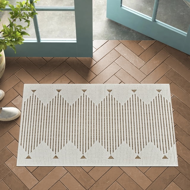 Rug Branch Maise Abstract Indoor Outdoor Area Rug in beige and brown with a geometric pattern of vertical stripes and triangles, sized 2'7" x 4'11", placed on brown herringbone tile floor near open blue doors and a plant, ideal for entryways, kitchens, or hallways and suitable for high-traffic areas.