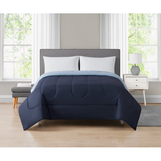 Mainstays Couette Réversible Bleu Marine Double/grand Lit sur un Lit Gris Rembourré, avec devant Bleu Marine et Côtés Inversés Bleu Pâle en Microfibre polyester Matelassée. la Couette 86 par 86 Pouces Est Présentée dans une Chambre Éclatante avec Rideaux Blancs, Plancher de Bois, une Table de Nuit Blanche avec une Lampe Géométrique et un Banc Gris, Convient à une Literie Polyvalente et Douillette dans les Chambres d'Adultes Ou d'Enfants.