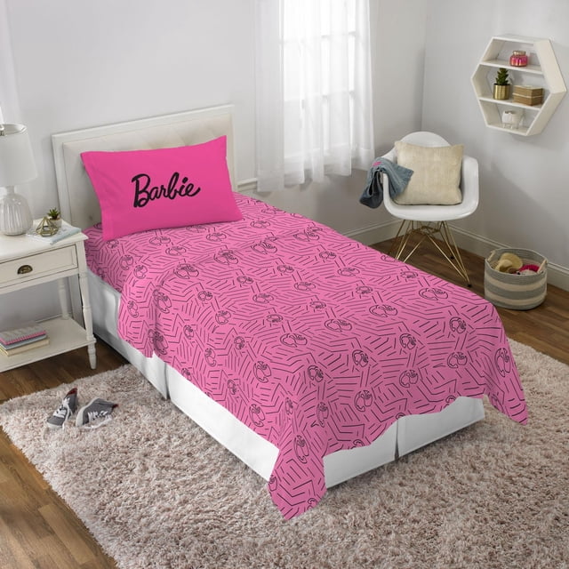 Barbie "Barbie Chevron" Twin Sheet Set with bright pink microfiber sheets featuring a black chevron pattern and Barbie face icons, paired with a matching pillowcase displaying the black Barbie logo, styled on a twin bed in a child's bedroom with white walls and modern furniture.