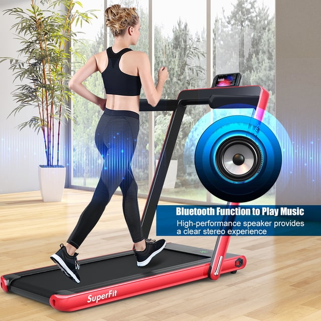 Patiojoy Tapis Roulant Électrique Pliant 2 en 1 avec Haut-Parleur Bluetooth en Rouge, Affiché dans un Espace Intérieur Moderne. une Femme Fait du jogging sur le Tapis Roulant, Qui Sert Aussi de Tapis Roulant sous le Bureau une Fois Plié. Caractéristiques Incluant un Cadre en Acier Robuste, un Écran LED, un Support pour Téléphone, un Haut-Parleur Bluetooth et une Ceinture de Course Antidérapante à 5 Couches pour Amortir les Genoux. Idéal pour la Marche, le jogging et la Course avec des Vitesses de 0,6 Mi/h à 7,5 Mi/h.