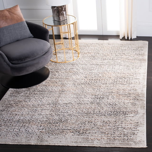 Safavieh Mayflower Hieren Geometric Area Rug in soft neutral tones with a distressed vintage patina and subtle geometric pattern, power-loomed synthetic yarns for durability, displayed on dark hardwood flooring beside a grey swivel chair with a brown cushion and a gold metal side table with glass top and white lamp near white French doors with sheer curtains, ideal for adding timeless elegance to living rooms.