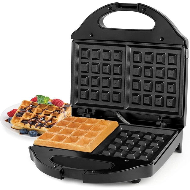 Salton Essentials Gaufrier Style Belge 2 Tranches Noir avec Plaques Antiadhésives. le Gaufrier Ouvert Affiche Ses Doubles Plaques de Cuisson, l'Une avec une Gaufre Dorée et l'Autre Vide. une Assiette de Gaufres Préparées Nappée de Sirop, de Baies et de Chocolat Est visible en Arrière-Plan. design Compact avec Poignée Isolée et Voyants Indicateurs pour une Utilisation Facile.