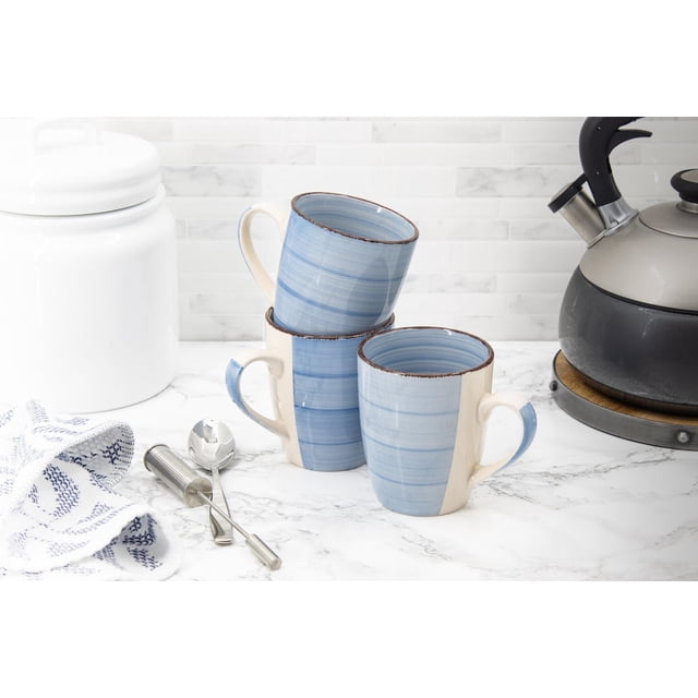 Hometrends Ensemble de 3 Sophia Mugs sur Comptoir en Marbre Blanc, avec une construction en Grès durable au design Bicolore Bleu et Crème, de Subtiles Rayures Horizontales et des accents de Rebord Bruns. l'Ensemble Est Montré avec un Infuseur à Thé et une Cuillère en Acier Inoxydable Près d'Un Contenant en Céramique Blanc et d'Une Bouilloire Noire pour Cuisinière, Idéal pour le Plaisir Quotidien du Café Ou du Thé.