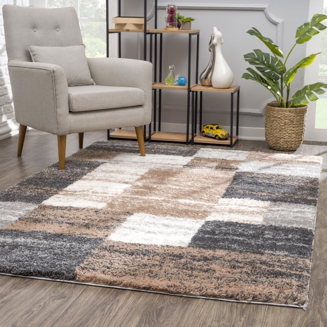 Rug Branch Rétro Collection Tapis Moderne Géométrique pour Aire avec texture shag à Haute Densité en beige, Gris, Blanc et Brun, Blocs Géométriques sur un Plancher de Bois, Montré avec un Fauteuil Rembourré Gris Pâle, une Unité d'Étagères en Métal Noir et Bois avec des Articles Décoratifs, et un Panier Tissé avec une Plante Verte, Convient aux Salons Modernes Ou aux Aires de Jeux.