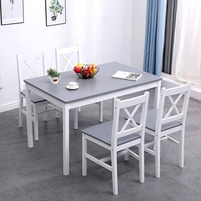 Soges 5 Pieces Dining Table Set, a compact dining solution with a rectangular pine wood table featuring a gray top and white frame, accompanied by four matching chairs with cross-back designs and gray seats. Perfect for small spaces like breakfast nooks, studio apartments, or dining rooms. The set is displayed in a modern dining area with a light grey floor, white walls, and blue curtains.