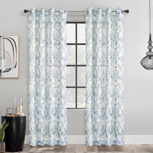 Loft Living Jennifer Botanical Print Grommet Single Curtain Panel light-filtering 52" x 95" in grey, featuring two front-facing panels with a blue botanical leaf pattern on white faux linen fabric, hanging on a silver rod with grommet headers in a modern room with light grey walls, wooden floor, abstract wall art, black side table with glass decor, and a black wire pendant light. These light filtering curtains provide privacy while allowing natural light and are ideal for stylish window treatments.
