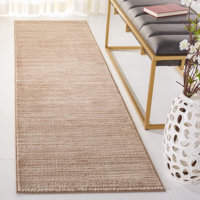 Safavieh Vision Adrasteia Overdyed Solid Area Rug in light brown with subtle horizontal texture, shown on a white floor beside a gold metal bench with black cushion and a white decorative vase with flowers, ideal for contemporary living or family rooms and suitable as an accent rug.