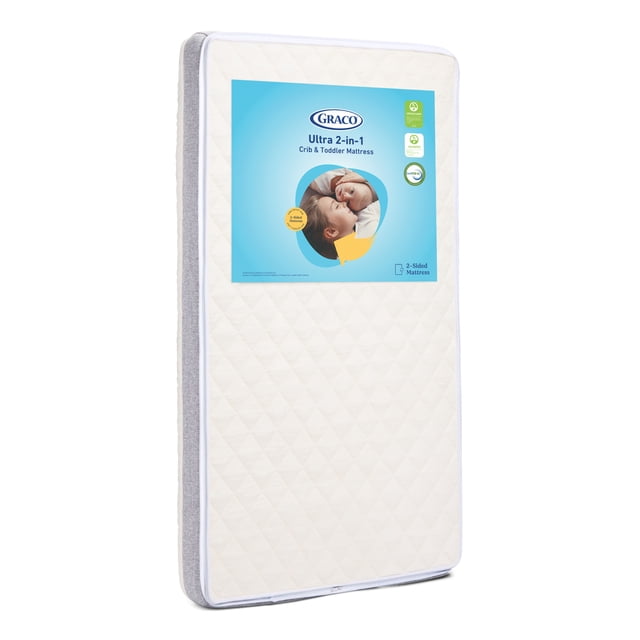 Graco Ultra 2-in-1 Premium Crib and Toddler Mattress standing upright with quilted white sleep surface and grey fabric sides, featuring a blue label with the Graco logo and product details, designed to fit any standard full-size crib or toddler bed.