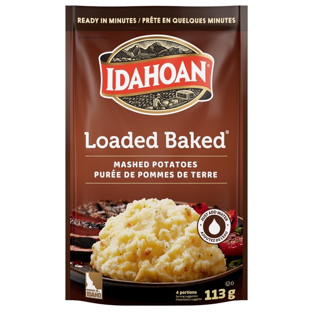 IDAHOAN LOADED BAKED POUCH showing a brown package with the Idahoan logo and bilingual text, featuring creamy mashed potatoes on a plate with grilled meat and vegetables, 113 g pouch serving 4 portions, ready in minutes by adding water, suitable for quick and easy potato side dishes.