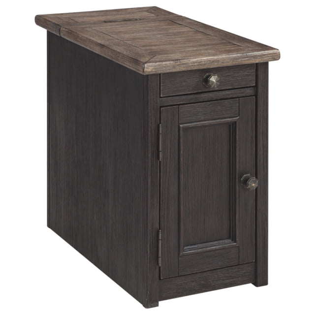 Signature Design by Ashley Tyler Creek Rustic Chair Side End Table with Pull-Out Tray & USB Ports, Brown. This compact end table features a textured black finish with a weathered gray-brown wood grain top. It includes a pull-out tray with two cup holders, a cabinet door with dark bronze-tone hardware, and two USB charging ports. Made of veneers, solid wood, and engineered wood, it combines farmhouse and traditional styles. Ideal for living rooms as a storage solution or accent piece.