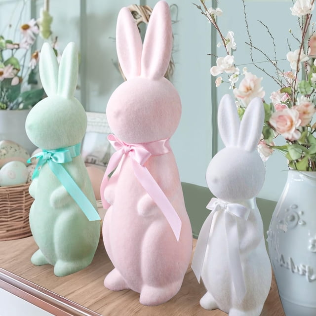 Easter Decorations - 3 Pack Pastel Flocked Bunny Kit featuring three plush bunnies in pink, green, and white, each adorned with ribbon details. The bunnies come in small (10 inches), medium (13 inches), and large (16 inches) sizes, with a flocked texture for a fuzzy feel and button noses for added charm. Displayed as spring table centerpieces, these lightweight and free-standing bunnies are perfect for indoor decor, including mantels, doors, or Easter-themed arrangements.