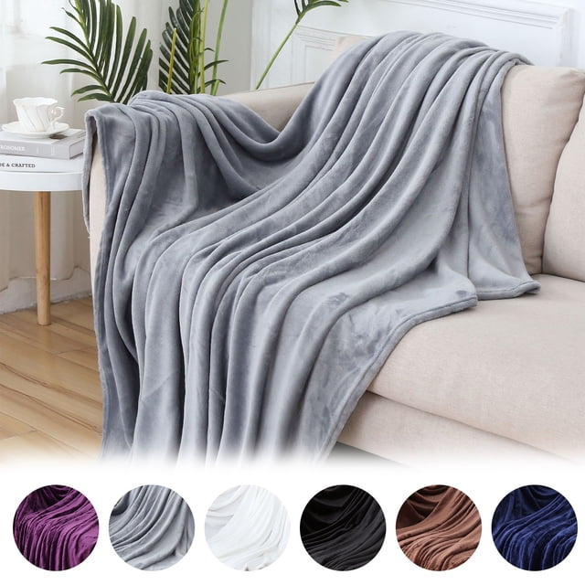 Vaidha Flannel Fleece Microfiber Throw Blanket in black, measuring 100x140x3cm, draped over a beige couch in a cozy living room. Made of soft polyester microfiber, this lightweight and warm blanket is ideal for couches, beds, and all-season use. Additional color options are displayed below the main image.