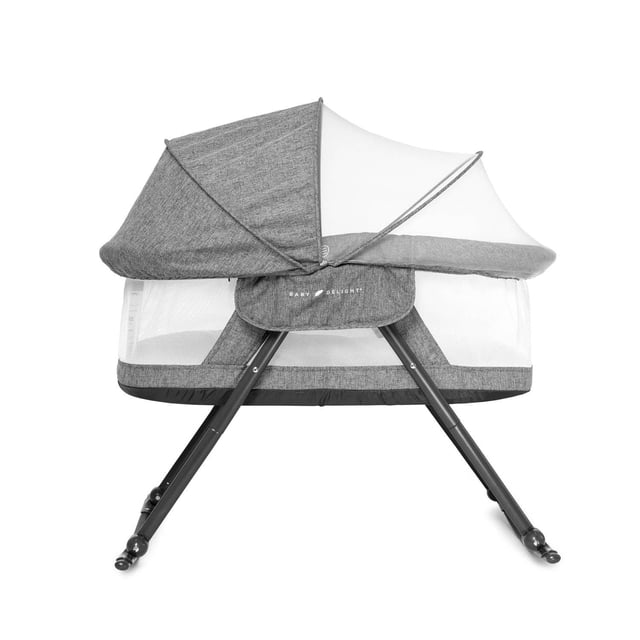 Baby Delight Slumber Deluxe Portable Rocking Bassinet in charcoal tweed fabric with breathable mesh walls, removable canopy, and black angled legs with wheels, designed for portability and small spaces, shown front-facing on white background.