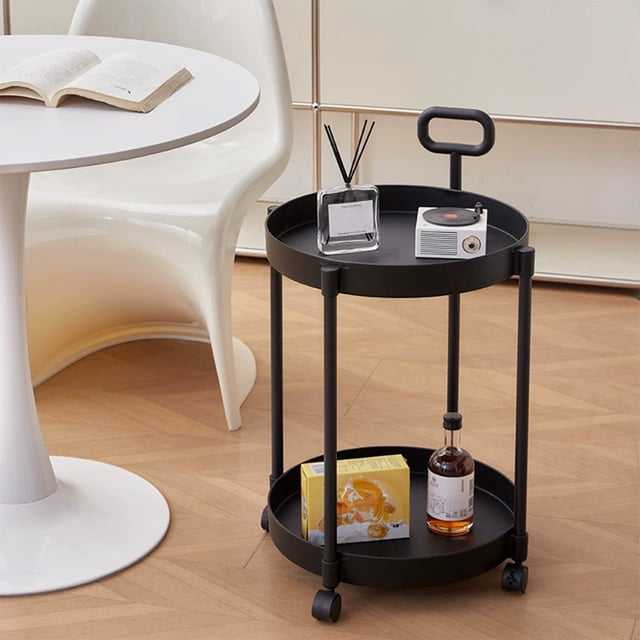 EGNMCR Home Coffee Table Movable Shelf Sofa Side Table Cart Bedside Shelf with Wheels, shown in a modern living room setting. The black, double-tiered organizer features a round design with two spacious shelves supported by four sturdy legs. Equipped with wheels for easy mobility, it is styled with decorative items like a reed diffuser, a small speaker, and a bottle. The compact size and sleek design make it ideal for living rooms, dorms, or home offices.