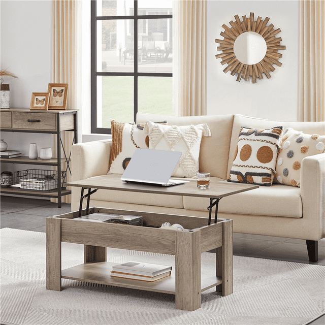 Yaheetech Table Basse à Plateau Relevable avec Compartiment Caché et Tablette Ouverte, Gris, Exposée dans un Salon Moderne au Décor Neutre. la Table Présente un design à Plateau Relevable Idéal pour les Repas sur le Côté du Sofa Ou l'Écriture, avec un Compartiment de Rangement Caché en Dessous pour Ordinateurs Portables et Télécommandes. l'Étagère Ouverte Inférieure Tient des Livres et des Articles de Déco. Fabriquée en MDF CARB P2 avec une Finition Grise Résistante à l'Eau, Elle Complète l'Esthétique Rustique de Style Ferme et les Petits Espaces.