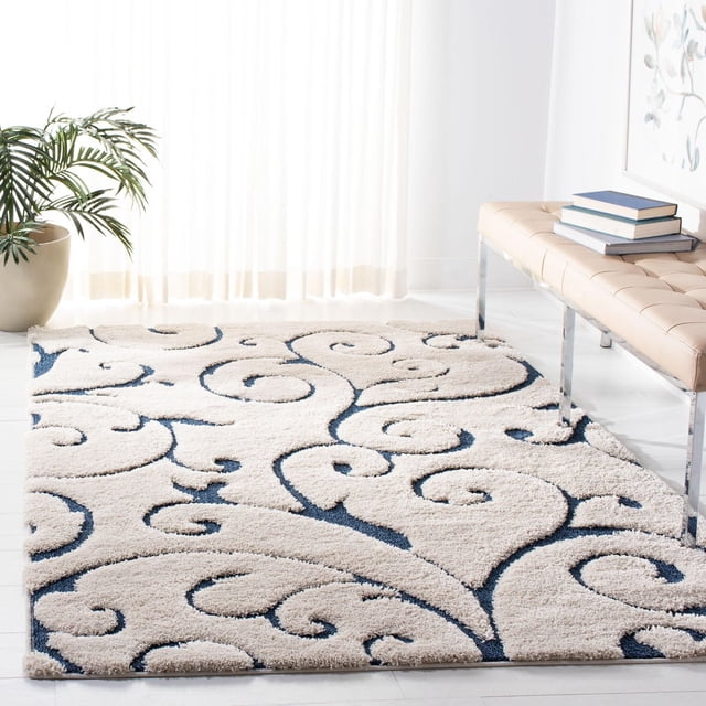 SAFAVIEH Florida Tapis Shag à Vignes Florales de Douglas, Présentant une Peluche crème à Poil Haut-Bas avec des Motifs de Vigne Damassée Bleu Foncé, Placé sur un Plancher Clair dans une Pièce Éclairée au Soleil, à Côté d'Un Banc Capitonné beige avec des Livres et une Plante en Pot Verte, Près de Voilages Transparents, Convient pour Ajouter de la texture et du Confort aux Espaces de Vie.