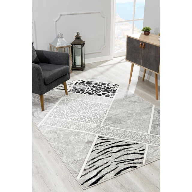 Rug Branch Paillasson Moderne Géométrique avec base Grise et Motifs d'Animaux Noir et Blanc au design patchwork Géométrique, Posé sur un Plancher de Bois Clair à Côté d'Un Fauteuil Gris Foncé et d'Une Armoire en Bois dans un Espace de Vie Intérieur Lumineux, Idéal comme Tapis d'Accent.