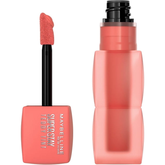 Teddy Tint, Soft Lip Gloss by Maybelline New York showing a close-up of the coral pink matte lip stain bottle with the applicator wand removed, featuring a soft textured tip coated in tint, designed for up to 12 hours of long-lasting, smudge-proof, no-transfer lip colour with a lightweight finish, also suitable for creating subtle cheek colour.